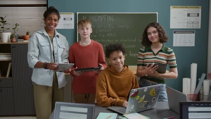 Medium portrait of four multicultural young students with laptops and digital tablets standing in front of blackboard with artificial intelligence prompt algorithm during STEM lesson at school - Powered by Adobe
