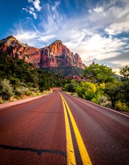 A road stretches towards a majestic mountain, illuminated by sunset hues, under a vibrant sky