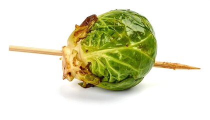 A roasted Brussels sprout on a wooden skewer, isolated against a clean white background