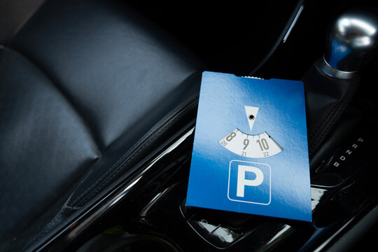 Close up blue parking disc in the car. Parking time restrictions in busy parking lots. Limited time duration park place zone.