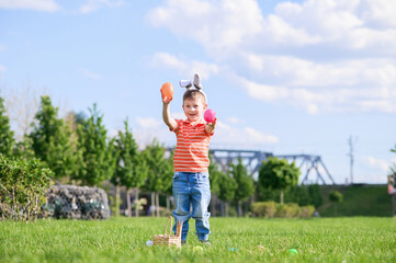 Fototapeta premium Smiling Boy Celebrating Easter Outdoors with Egg Hunt Basket
