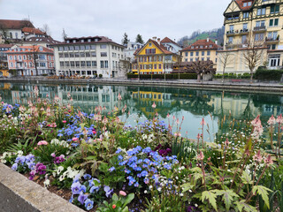 A lakeside town with the Aare River flowing through it. The city centre has old buildings and a picturesque wooden bridge. The highlight in the picture is the colorful flower beds. Thun, Switzerland.