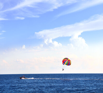 Picturesque view of sea and tourists on a parachute. Topic of summer vacation, travel, leisure and adventure for tourist. Parasailing in the sea. A popular tourist pastime with a parascending