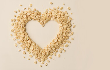 A heart-shaped frame crafted from rolled oats on a beige background for healthy living and breakfast themes