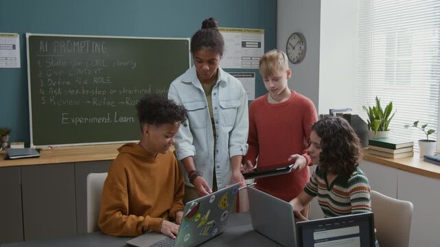 Medium full shot of teenage African American girl demonstrating artificial intelligence generative project to multiethnic classmates on digital tablet at STEM lesson in middle school or computer club