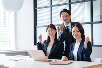 社内でガッツポーズをするカメラ目線の男女