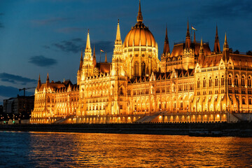 Fototapeta premium The Hungarian Parliament Building shines brilliantly at night, its golden lights reflected in the Danube River