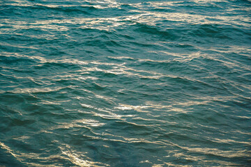 Water ripple surface texture, Rippling water surface with sunset reflection ripples. Golden sunset on rippling ocean waves. Tranquil water ripples reflecting sunlight.