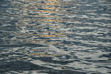 Water ripple surface texture, Rippling water surface with sunset reflection ripples. Golden sunset on rippling ocean waves. Tranquil water ripples reflecting sunlight.