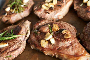 Steak with garlic and rosemary on a baking sheet, close-up