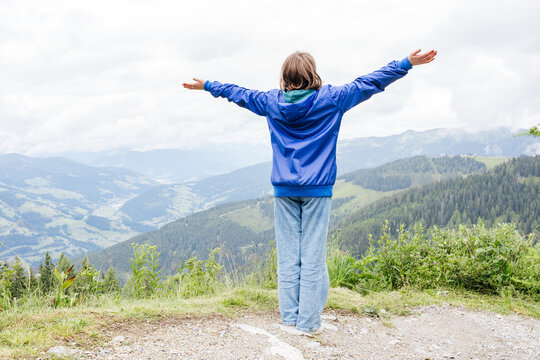 Youth with arms outstretched enjoying freedom on mountain landscape - Powered by Adobe
