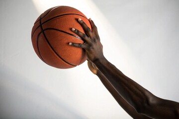 A basketball player is about to shoot a basketball through a hole in a wall
