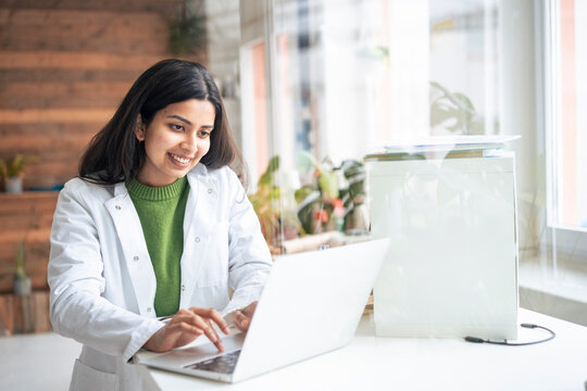 Doctor in lab coat working on laptop in modern medical laboratory
