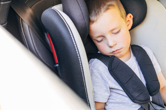 Child sleeping in car seat during travel with seatbelt fastened
