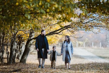 Pregnant family walking together in autumn nature park