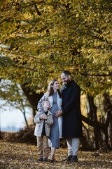 Family enjoying autumn day, anticipating new family member