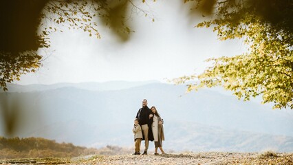 Family standing together in autumn mountains expecting baby