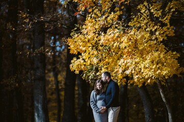 Expecting couple embracing outdoors during autumn season