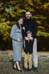 Pregnant woman with family standing in autumn nature