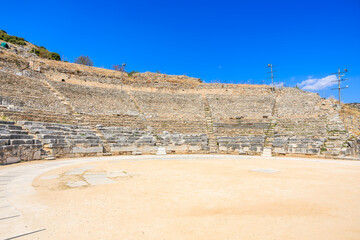 A large empty amphitheater with a blue sky above. Ruins of the ancient city of Philippi, Greece