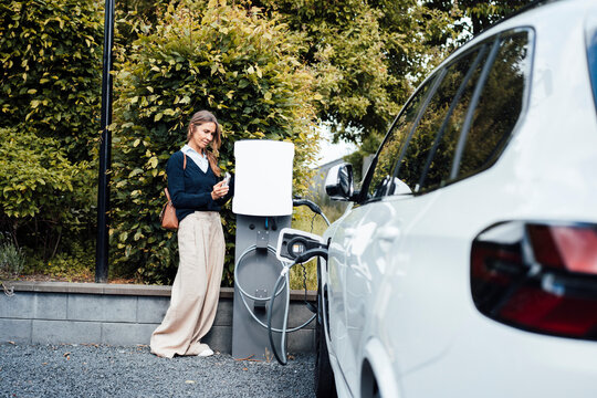 Businesswoman charging electric car at outdoor fast charging station