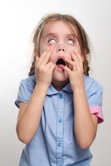 Young girl with surprised expression, eyes wide open, mouth agape, hands covering face. A candid...