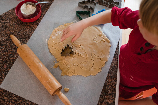 Overhead view of a Boy using a cookie cutter to make Christmas tree cookies