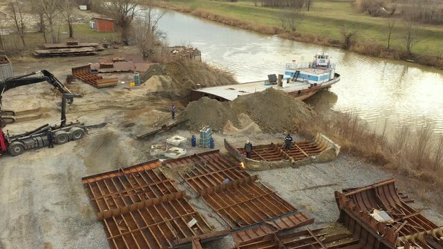 Above view on workers as they cutting parts of old large vessel into smaller pieces, barge, dismantling ship, cut out rusty metal for scarp, using acetylene torch, recycling, sparks are fly around.