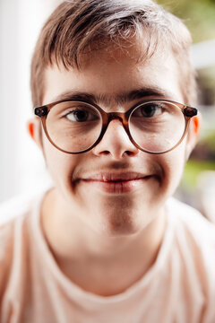 Portrait of smiling teenager with glasses and trisomy 21 indoors