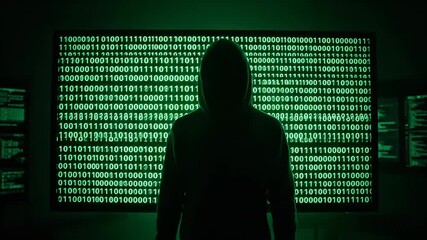 Mysterious hooded man stands in front of matrix style binary code wall. Hacker concept with digital data and network technology footage. - Powered by Adobe