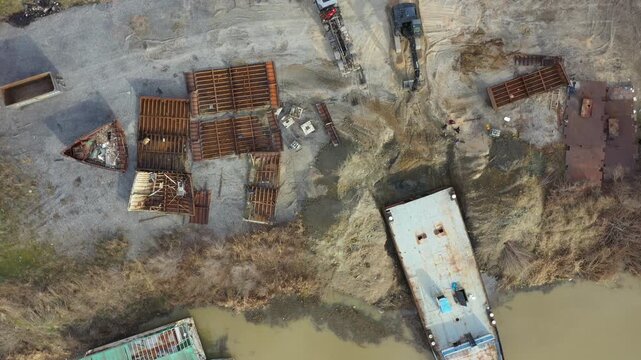 Above view on workers as cutting parts of old large vessel into smaller pieces, barge, dismantling ship, cut out rusty metal for scarp, excavator and tow truck are pull out part of old vessel's bed