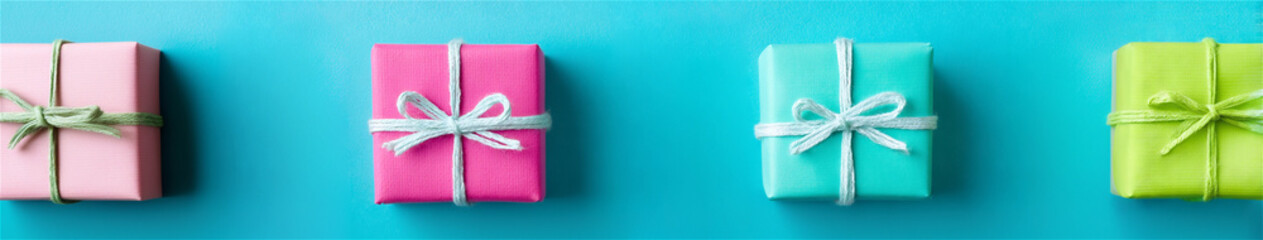 Four vibrant wrapped gift boxes with bows lined horizontally on a blue flat lay, evoking festive celebration, birthdays, holidays, and cheerful giving 