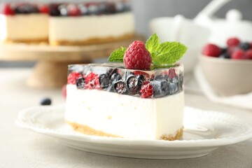 Piece of delicious cheesecake with berries and mint on light grey table, closeup