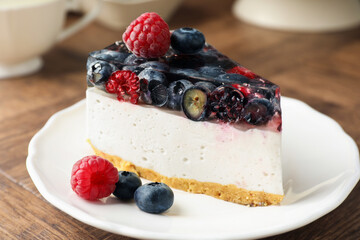 Piece of delicious cheesecake with berries on wooden table, closeup
