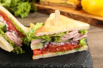 Tasty sandwiches with ham and vegetables on wooden table, closeup