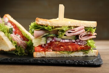 Tasty sandwiches with ham and vegetables on wooden table, closeup