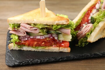 Tasty sandwiches with ham and vegetables on wooden table, closeup