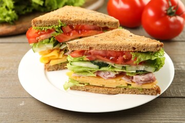 Tasty sandwiches with ham, cheese and vegetables on wooden table, closeup
