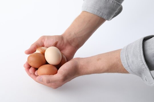 Man with raw chicken eggs on white background, closeup