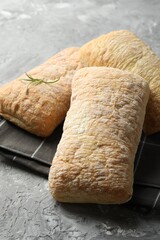 Fresh crispy ciabattas on grey textured table, closeup