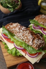 Tasty ciabatta sandwiches with cheese and vegetables on wooden table, closeup