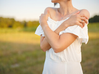 Beautiful woman in white dress standing in summer field during golden sunset in Croatia, warm sunlight, romantic evening mood, natural countryside atmosphere, soft wind and peaceful scene