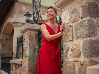 Woman in red dress walking narrow streets of old town Antalya during warm summer evening. Historic atmosphere and Mediterranean charm creates peaceful travel experience.