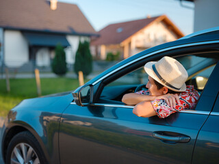 Traveler woman in red ethnic dress and hat drives car through scenic countryside of Croatia in summer. Surrounded by lush fields and forests, she enjoys peaceful and adventurous road trip
