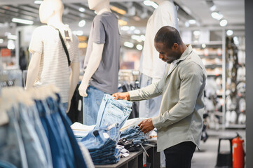 Stylish man choosing jeans in clothing store