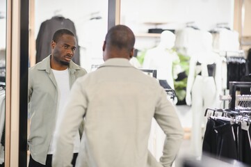 Obraz premium Stylish man choosing clothes in fashion store mirror