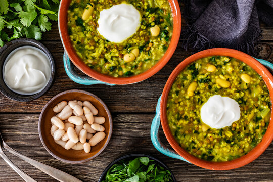 Aash-e Jow - persian barley soup on wooden table. Top view