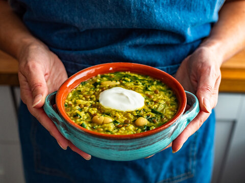 Woman holding bowl with Aash-e Jow - persian barley soup, close-up