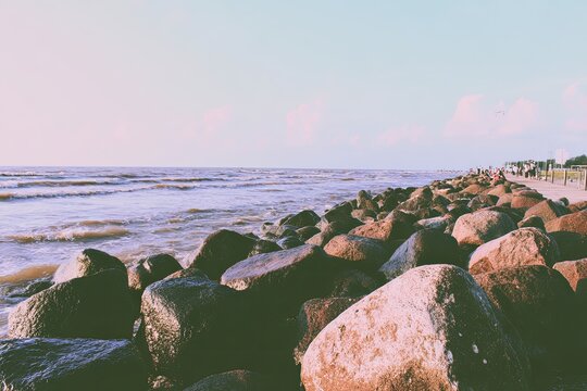 Rocky beach with ocean waves under a pale, bright sky