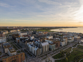 Aerial view of modern buildings casting long shadows under a golden sky as the sun sets over the shimmering baltic sea, Nyhamnen, Malmo, Sweden.